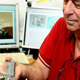 Ricor’s Yoav Zur holding a K508 cryocooler, the same one used in the Curiosity’s CheMin instrument shown on his computer screen.